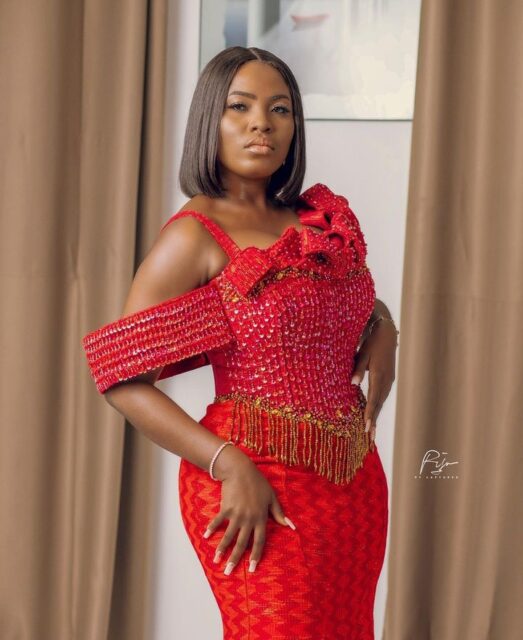 Woman in elegant red beaded dress posing.