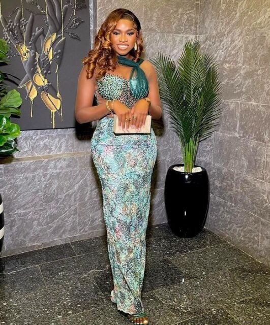 Woman in elegant patterned gown with clutch.