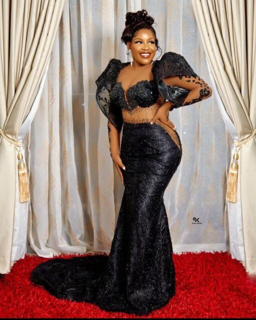 Woman in elegant black gown posing indoors.