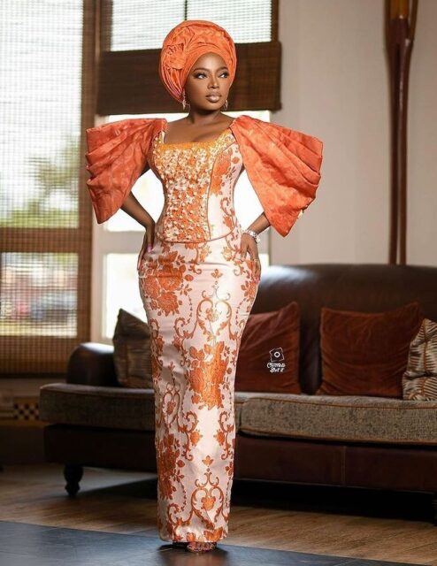 Woman in elegant orange traditional African attire.