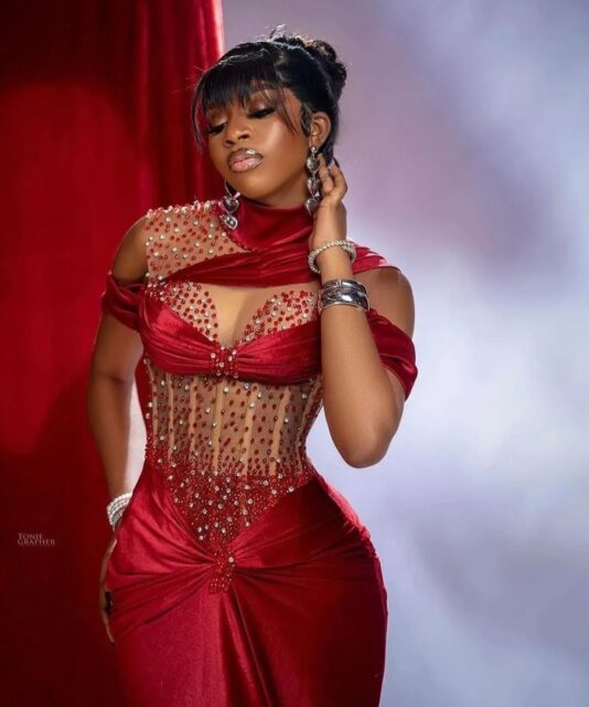 Woman in elegant red beaded dress posing.