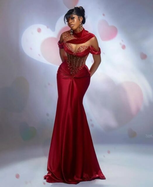 Woman in elegant red evening gown with hearts background.