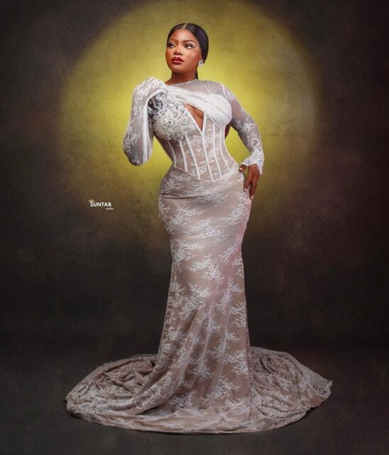 Woman in elegant lace gown posing.